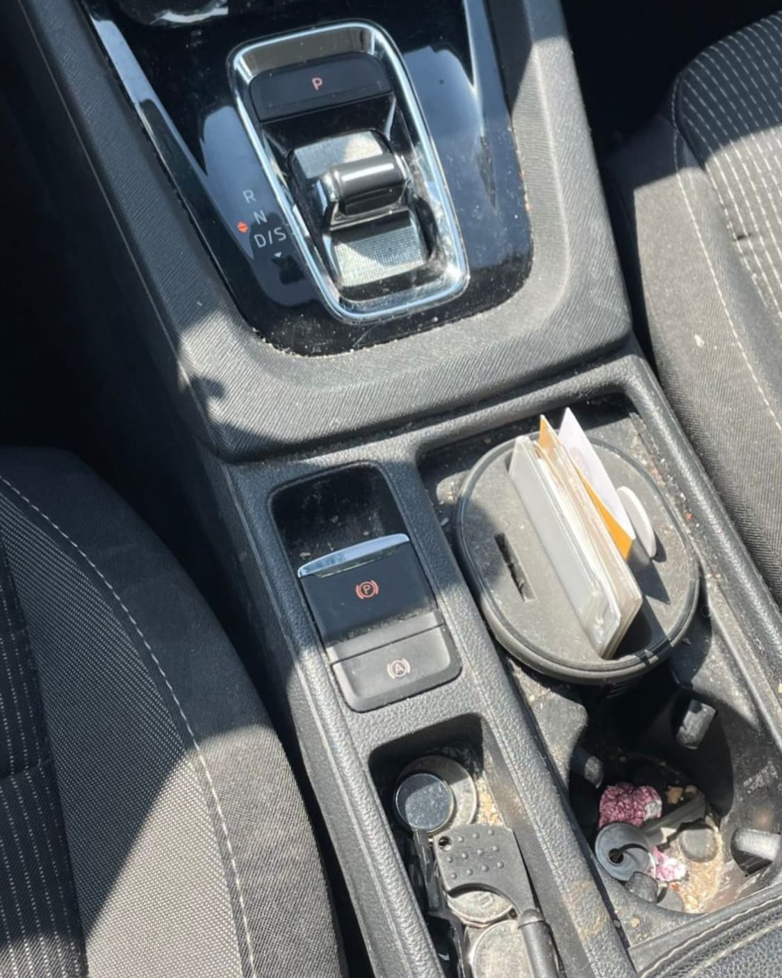 Voor: dezelfde middenconsole vol stof, kruimels en vuil in de bekerhouders